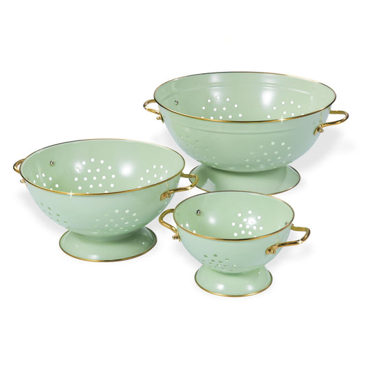 Set of three light green colanders with gold handles on a white background