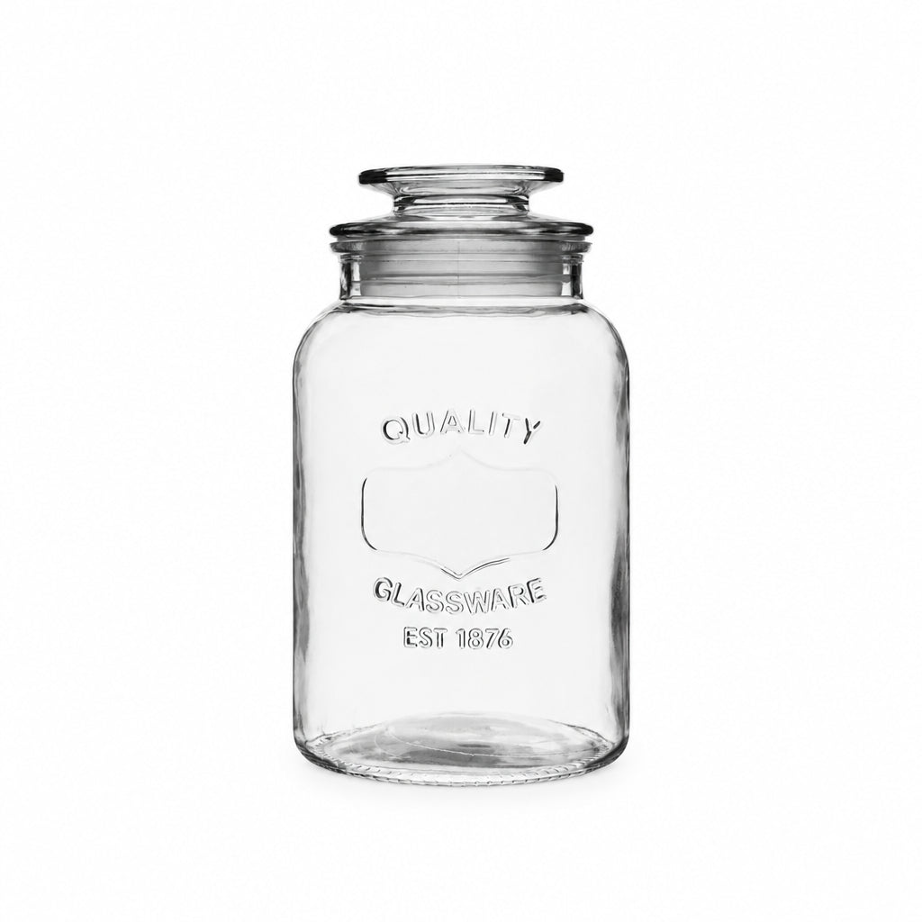 A clear glass jar with a matching glass lid, featuring embossed text that reads 'QUALITY GLASSWARE EST 1876' on the front.
