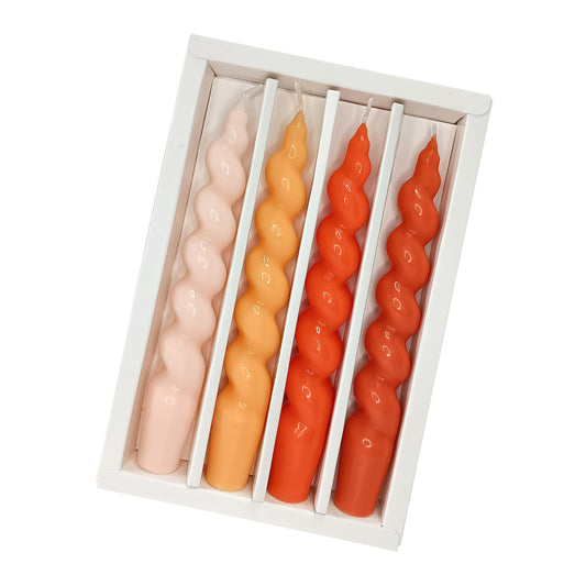 Set of four wavy candles in pink, orange, and red in a white box on a white background